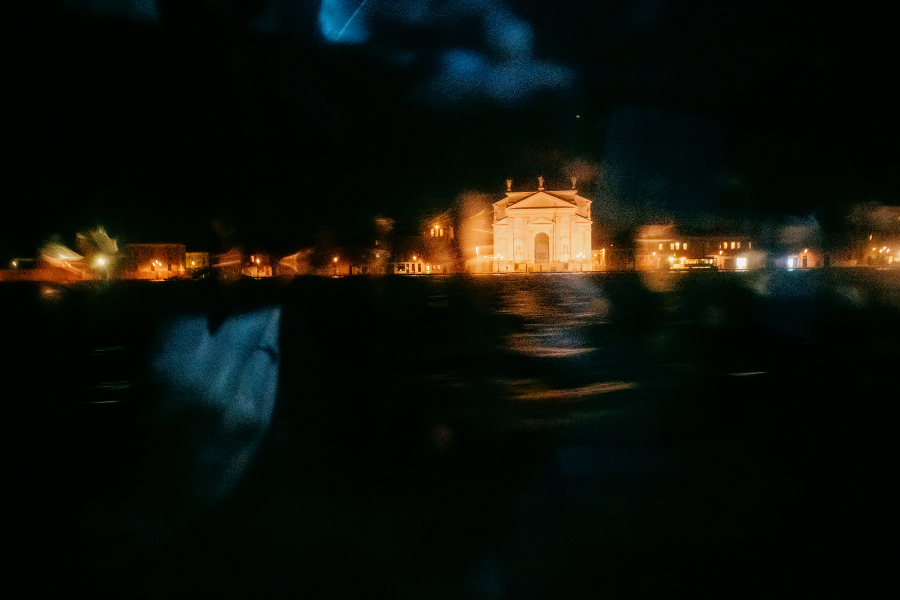 blurry picture of a waterfront church in Venice taken through the window of a speed boat at night